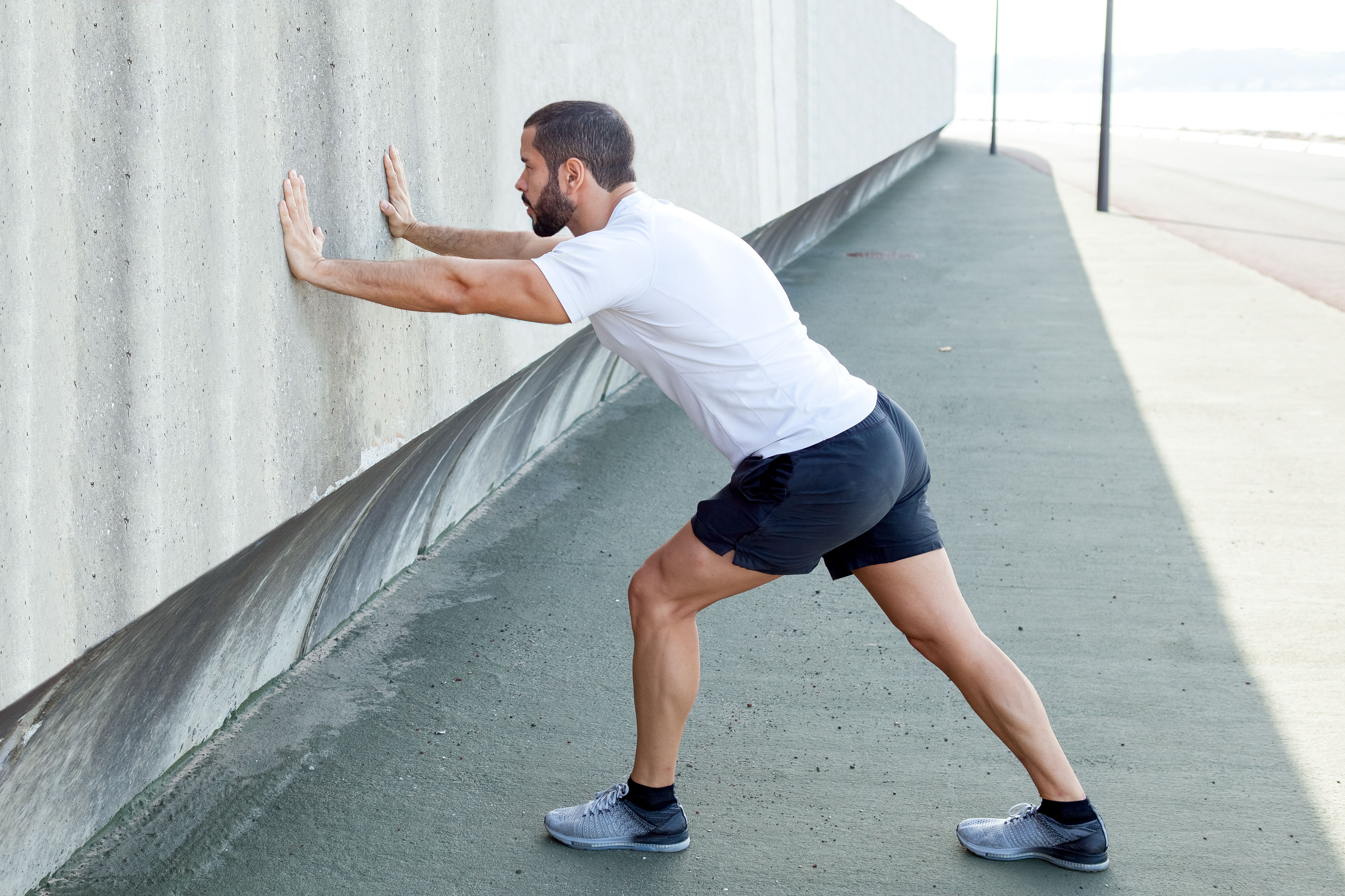 strong-man-stretching-calf-leaning-wall.jpg